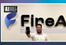 FireAI raises ₹2.5 crore from SucSEED Indovation Fund to accelerate enterprise AI growth Man in a white shirt takes a selfie in front of a large FineAI sign with the AI Brief logo nearby, smiling at the camera.
