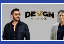 Devgn CineX strengthens South India presence with new cinema properties Two men pose in front of a gray backdrop with a 'DEVGN CINEX' logo, framed by a blue border and a vertical MEDIABRIEF label on the left.
