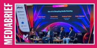 Panel discussion on 'How AI is Disrupting Media Planning' with four speakers on stage and a glowing backdrop.