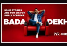 PVR INOX launches campaigns to drive moviegoing and audience engagement Promotional poster: a man sits in a red armchair against a red backdrop, slogan 'Some stories are too big for small screens' with bold 'BADA DEKHO' and PVR INOX logo; vertical MEDIABRIEF on the left.